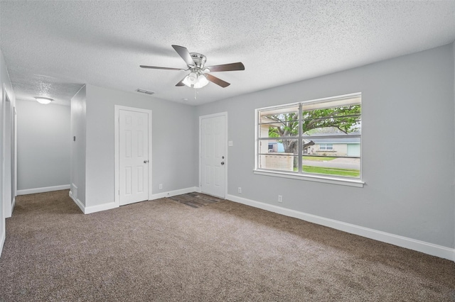 carpeted spare room with visible vents, a textured ceiling, ceiling fan, and baseboards