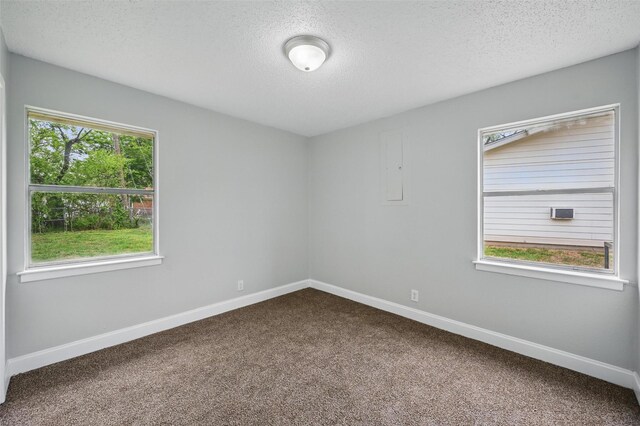 unfurnished room featuring baseboards, dark colored carpet, and a textured ceiling