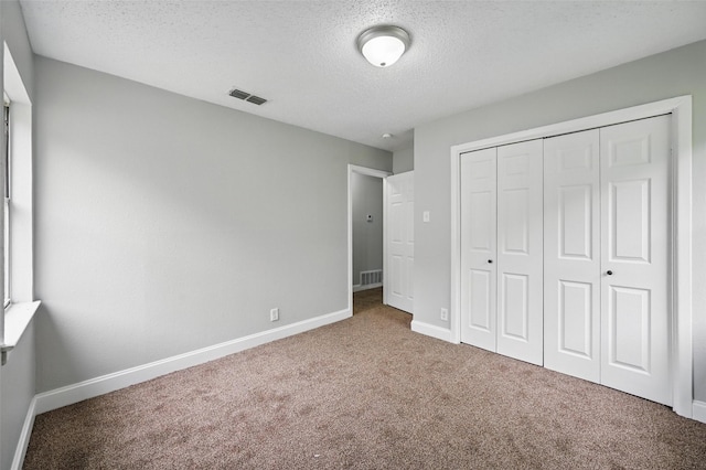 unfurnished bedroom with carpet flooring, a textured ceiling, visible vents, and baseboards