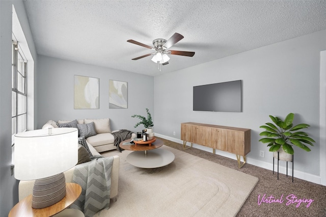 living area featuring a textured ceiling, ceiling fan, baseboards, and carpet