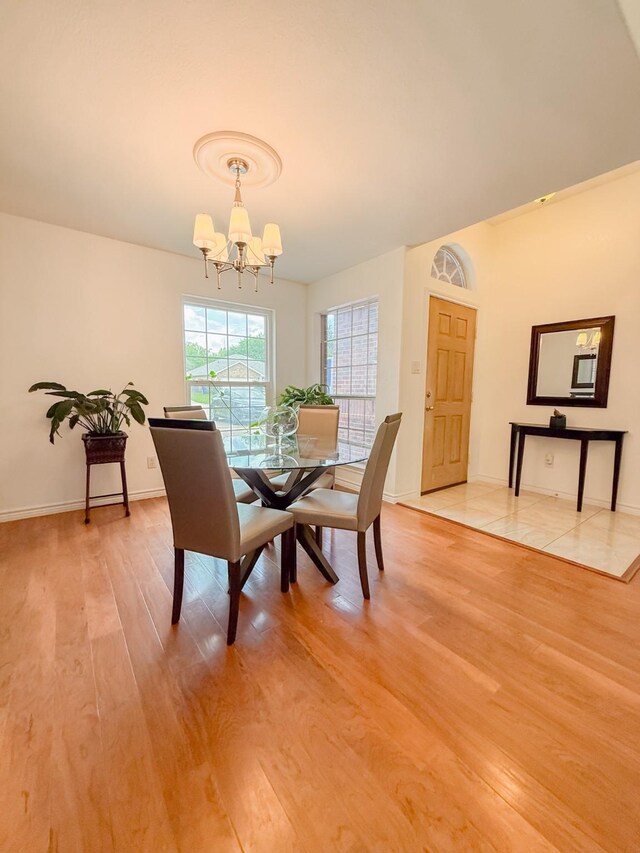 dining room with baseboards, a notable chandelier, and light wood-type flooring