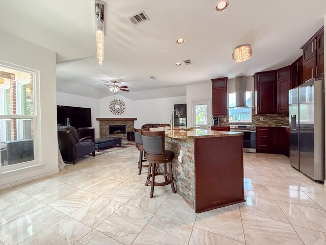kitchen with decorative backsplash, ceiling fan, visible vents, appliances with stainless steel finishes, and a fireplace