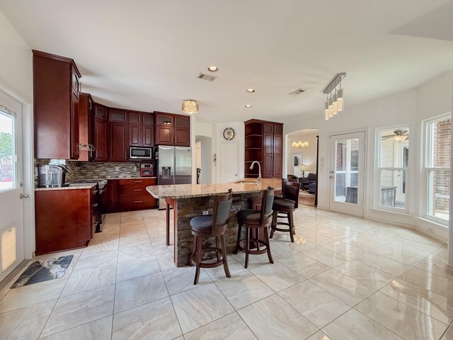 kitchen featuring backsplash, stainless steel appliances, visible vents, and marble finish floor