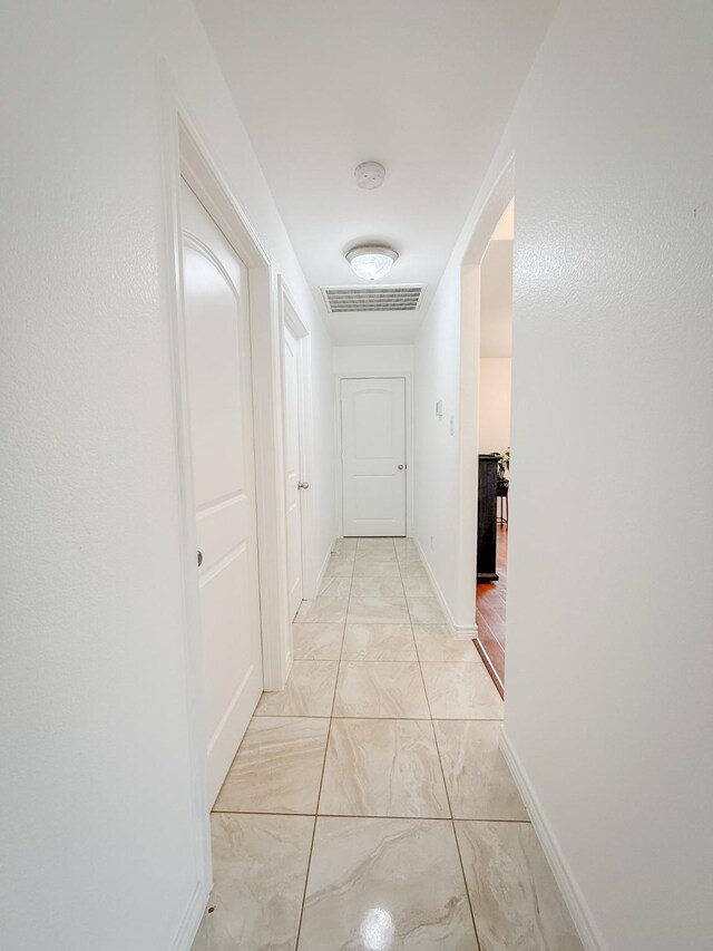 hall featuring arched walkways, baseboards, visible vents, and marble finish floor