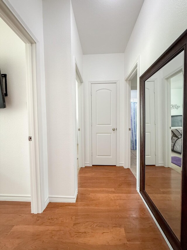 hall featuring baseboards and light wood-style floors