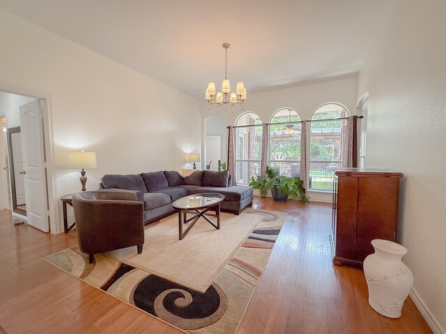 living area with baseboards, light wood-style flooring, and a chandelier
