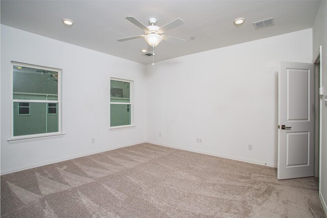 unfurnished room featuring visible vents, a ceiling fan, and light carpet