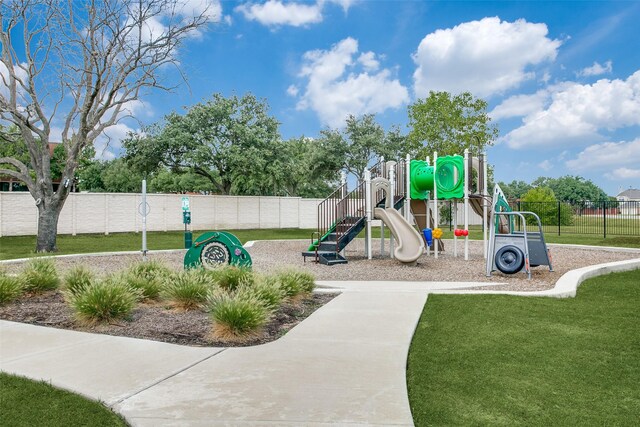 communal playground featuring a lawn and fence