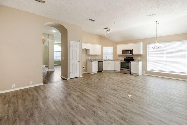kitchen featuring appliances with stainless steel finishes, arched walkways, a textured ceiling, and white cabinetry