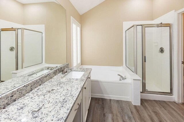 full bath featuring vanity, wood finished floors, lofted ceiling, a bath, and a stall shower