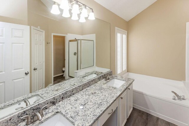 full bath featuring wood finished floors, double vanity, a sink, and a stall shower