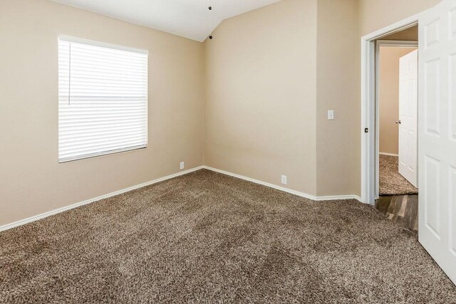 carpeted spare room with baseboards and vaulted ceiling