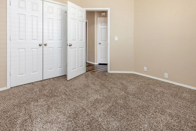 unfurnished bedroom with baseboards, carpet, and a closet