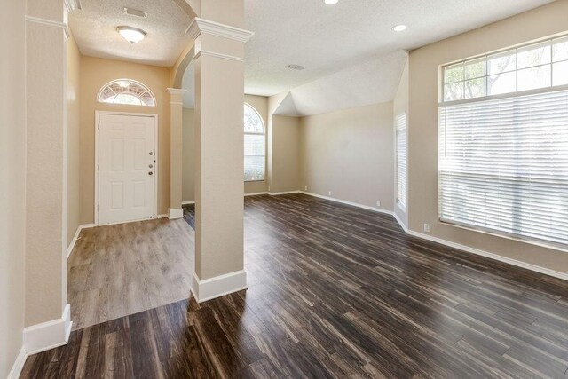foyer entrance with ornate columns, baseboards, wood finished floors, and visible vents