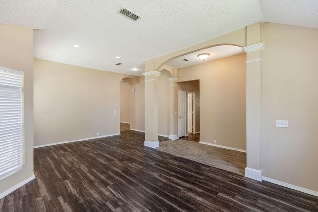 unfurnished room with decorative columns, dark wood-type flooring, and visible vents