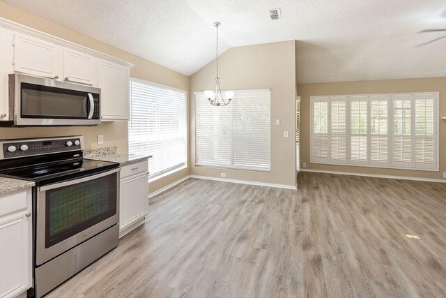 kitchen with an inviting chandelier, light wood-style flooring, stainless steel appliances, white cabinetry, and vaulted ceiling