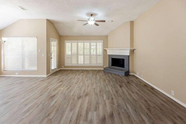 unfurnished living room with visible vents, a fireplace, a ceiling fan, wood finished floors, and vaulted ceiling