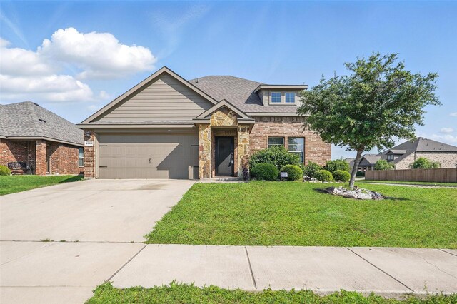 craftsman-style house featuring driveway, a front yard, a garage, fence, and stone siding