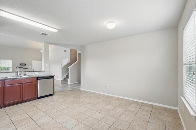 kitchen with light stone counters, a sink, light tile patterned floors, stainless steel dishwasher, and visible vents