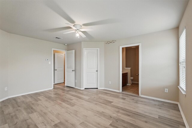 unfurnished bedroom with baseboards, light wood-type flooring, connected bathroom, and visible vents