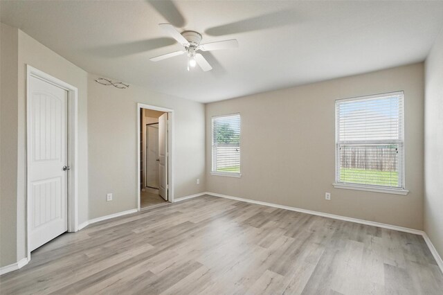 unfurnished bedroom with light wood-style floors, a ceiling fan, baseboards, and ensuite bath