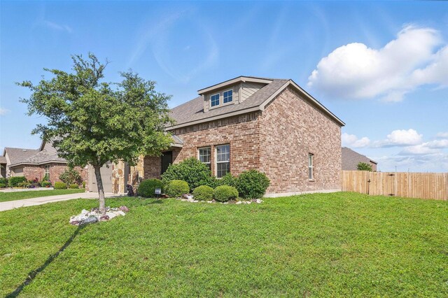 traditional-style house with concrete driveway, brick siding, fence, and a front lawn