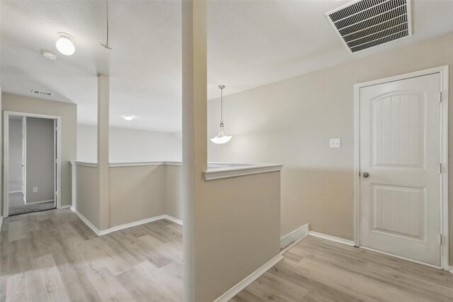 hallway with baseboards, wood finished floors, and visible vents