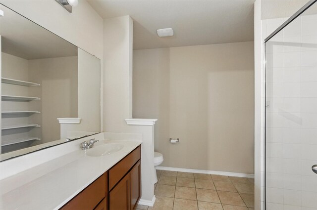 full bathroom featuring vanity, toilet, baseboards, tile patterned floors, and a tile shower