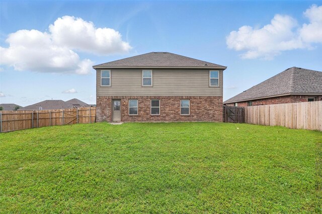 rear view of property with a fenced backyard, a lawn, and brick siding