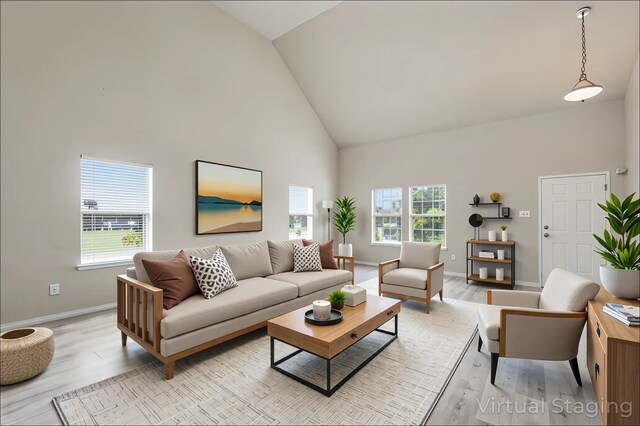 living area with baseboards, light wood-style flooring, and high vaulted ceiling