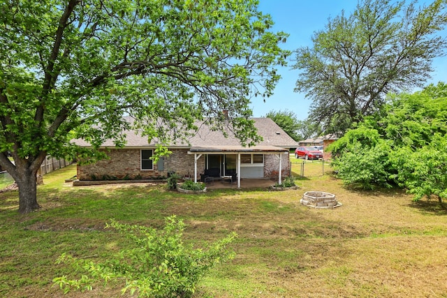 back of property featuring a lawn, a patio area, and a fire pit