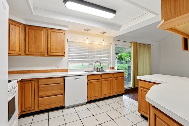 kitchen with a sink, white appliances, light countertops, brown cabinetry, and decorative light fixtures