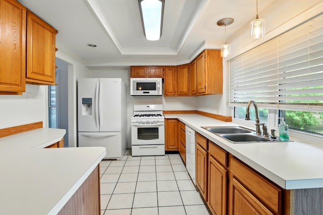 kitchen with a sink, light countertops, a tray ceiling, and white appliances