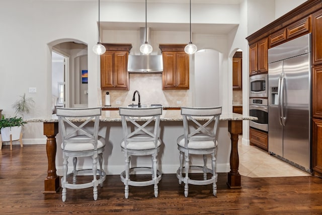 2206 Glasgow Dr, Trophy Club, TX 76262 - kitchen with built in appliances, arched walkways, an island with sink, backsplash, and light stone counters