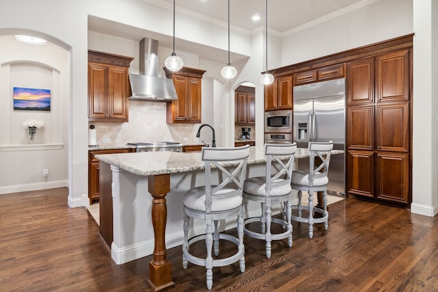 2206 Glasgow Dr, Trophy Club, TX 76262 - kitchen featuring wall chimney range hood, built in appliances, an island with sink, backsplash, and crown molding