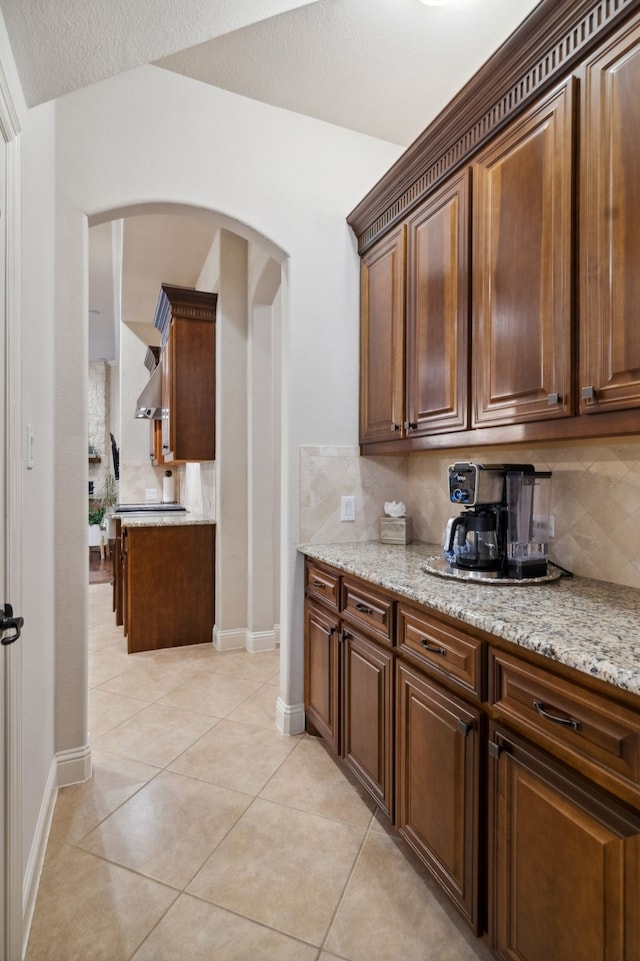 2206 Glasgow Dr, Trophy Club, TX 76262 - kitchen with arched walkways, backsplash, baseboards, and light stone countertops