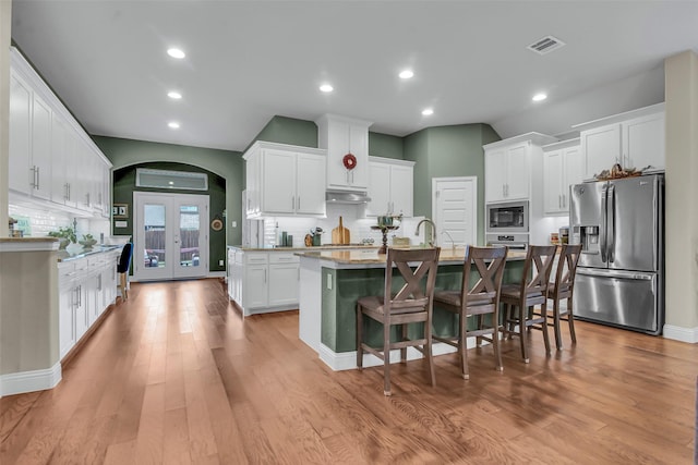 3213 Timberline Dr, Melissa, TX 75454 - kitchen featuring stainless steel fridge, a kitchen island with sink, built in microwave, decorative backsplash, and visible vents