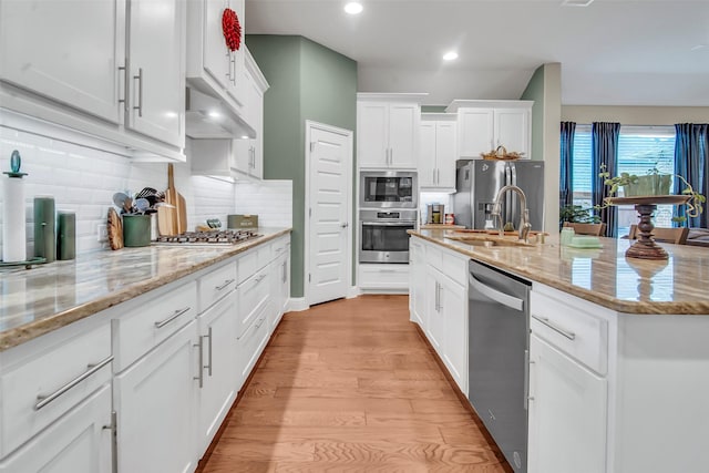 3213 Timberline Dr, Melissa, TX 75454 - kitchen featuring white cabinets, a sink, light wood-style flooring, stainless steel appliances, and under cabinet range hood