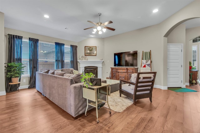3213 Timberline Dr, Melissa, TX 75454 - living room with ceiling fan, light wood-style floors, arched walkways, a glass covered fireplace, and baseboards