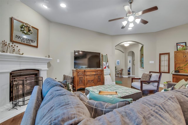 3213 Timberline Dr, Melissa, TX 75454 - living room with a ceiling fan, a glass covered fireplace, wood finished floors, baseboards, and arched walkways