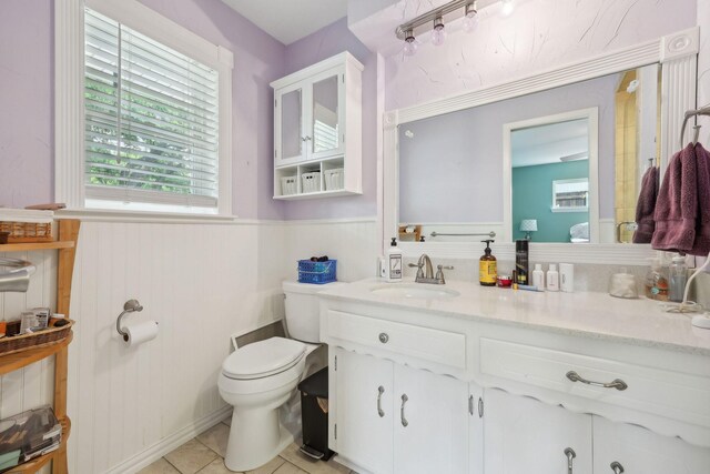 bathroom featuring vanity, wainscoting, tile patterned flooring, and toilet