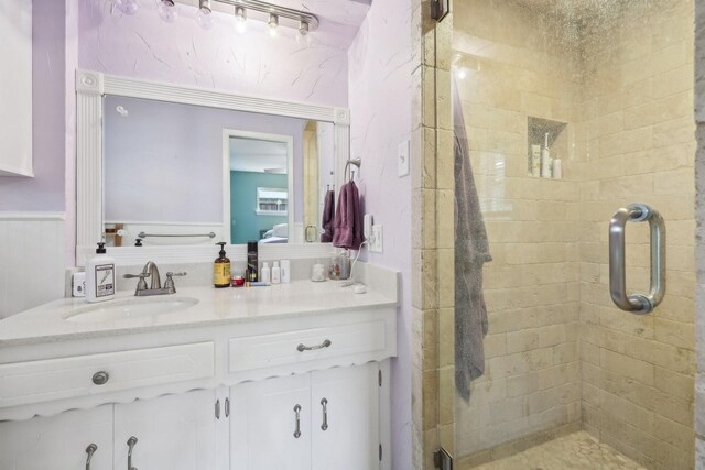 bathroom featuring vanity, a wainscoted wall, and a stall shower