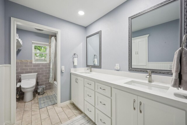 bathroom featuring double vanity, toilet, tile walls, and a sink