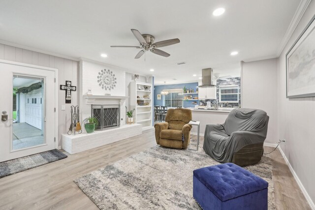 living room with ornamental molding, a brick fireplace, wood finished floors, recessed lighting, and a ceiling fan