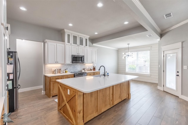 kitchen featuring appliances with stainless steel finishes, a sink, baseboards, light countertops, and light wood-style floors