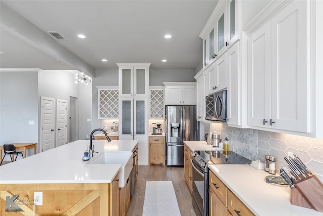 kitchen featuring visible vents, dark wood-type flooring, tasteful backsplash, a sink, and stainless steel appliances