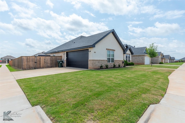 view of front of property featuring brick siding, fence, a front lawn, concrete driveway, and an attached garage
