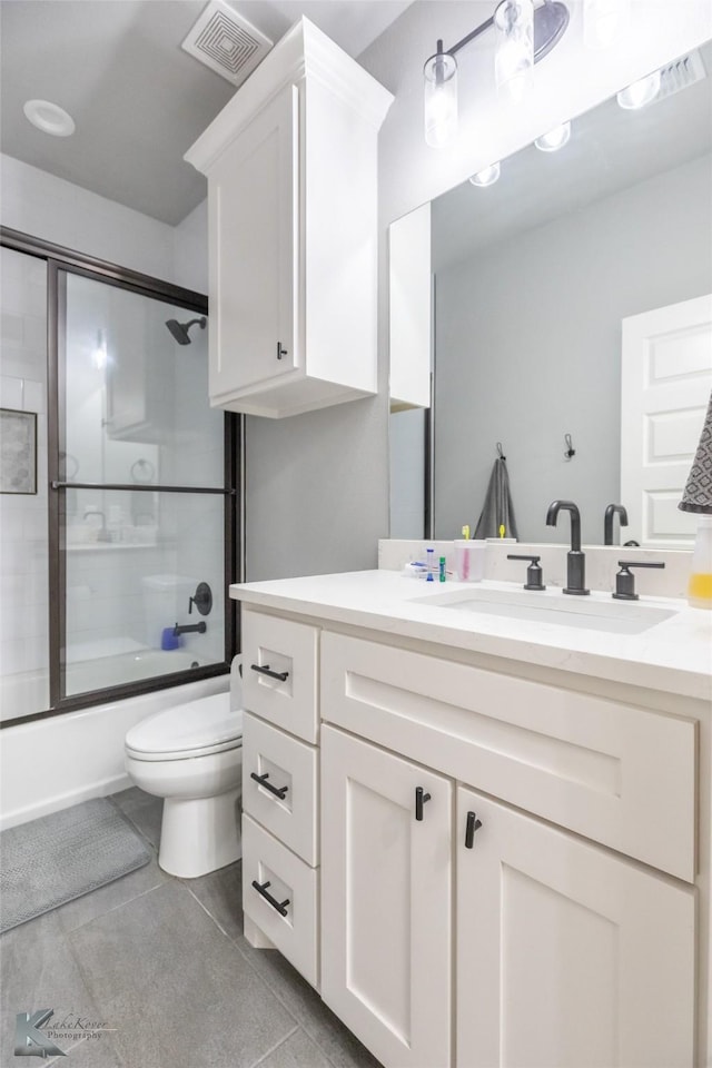 full bathroom featuring visible vents, vanity, toilet, bath / shower combo with glass door, and tile patterned floors