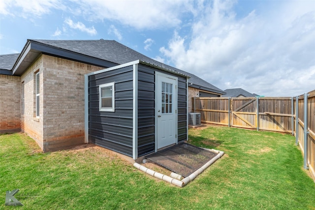 view of outbuilding with a fenced backyard, central AC, an outbuilding, and a gate