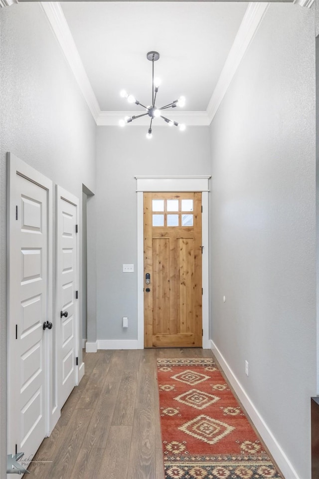 foyer with crown molding, baseboards, wood finished floors, and a chandelier